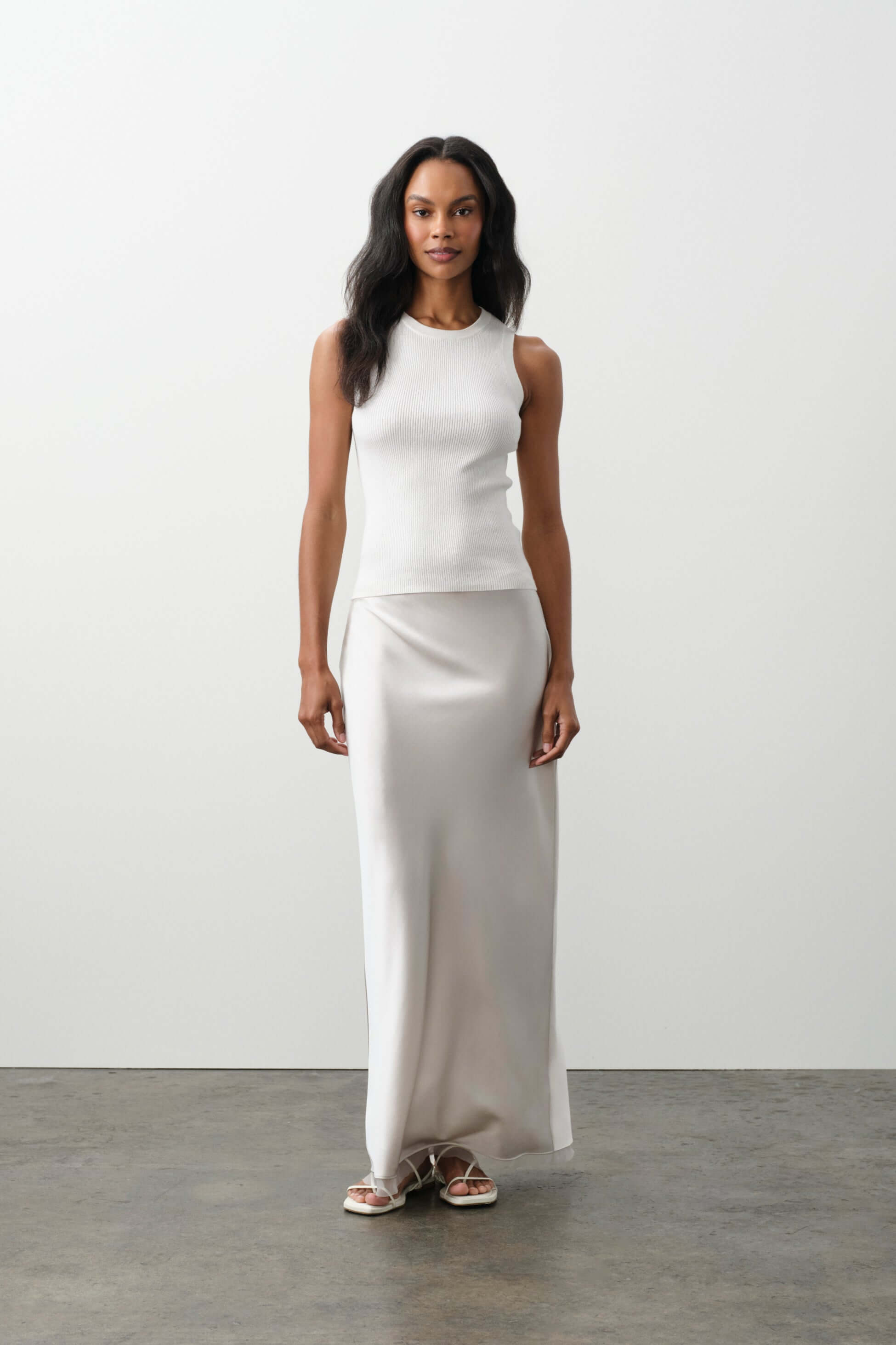 Model showcasing elegant silver maxi dress and white top from the Bottoms collection.